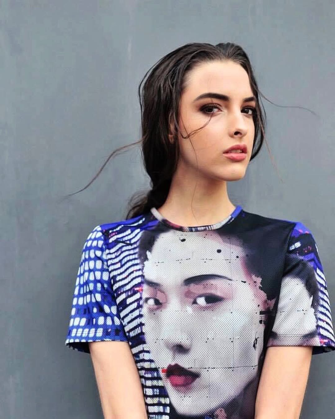 Modella con t-shirt stampata, trucco occhi intenso, su sfondo grigio